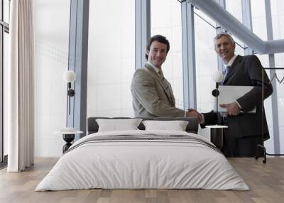 two businessmen shaking hands in front of large glass widows Wall mural