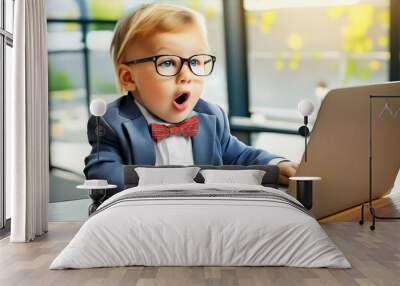 Caucasian toddler boy working at laptop with surprised and shocked expression, wearing suit and bow tie, copy space Wall mural