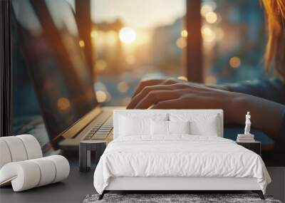 Close up of female hands typing on laptop keyboard, working at home, sunset in background, copy space Wall mural