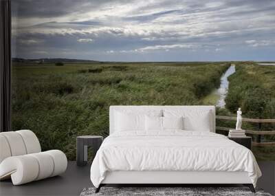 Landscape view of beautiful nature reserve with fence by bird watching hide wildlife lakes in marsh land by ocean in Cley Next the Sea Norfolk East Anglia uk reeds grass by water lake on Summer day  Wall mural