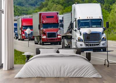 A solid line of eighteen-wheelers barrel down an interstate highway in Tennessee.  Heat waves rising from the pavement give a nice shimmering effect to vehicles and trees behind the lead truck. Wall mural