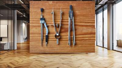 close-up of set of drawing tools including two metal dividers and one metal drawing compass isolated on wooden background Wall mural