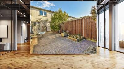 a backyard area with a ham on the wall, and a large wheel in the back yard next to it Wall mural