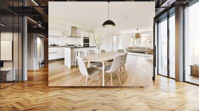 a kitchen, dining room and living area in an apartment with white walls and wood flooring the table is surrounded by grey chairs Wall mural