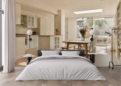 a kitchen and dining area in a house with white cabinets, wood flooring and an open door leading to the patio Wall mural