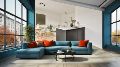 a kitchen and dining area in a house with white walls, hardwood flooring and black cabinetry on the island Wall mural