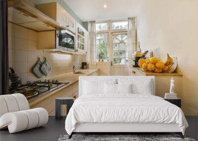 a kitchen with some fruit on the counter and an open window in the back wall to the room is white Wall mural