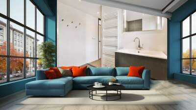 a modern bathroom with wood flooring and white walls, along with a large mirror on the wall above it Wall mural