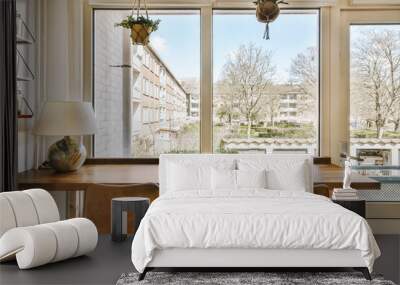 two chairs sitting at a table in front of a window with a view of the city outside and trees outside Wall mural