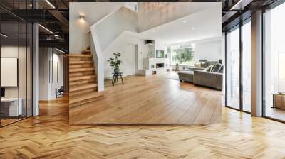 Cozy house interior with a wooden floor, large gray sofa, and stairs leading to the second floor Wall mural