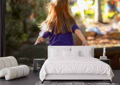 Little preschool girl with long hair running through garden at kindergarten Wall mural