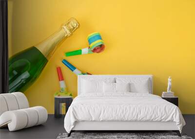 Bottle of champagne decorated with whistle party on a yellow background. Copy space. Wall mural