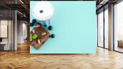 Flat lay. Coffee with brownie and cranberries on light green background. Wall mural