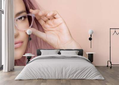 Closeup face of a gorgeous model girl with trendy clear glasses and colored pink hair posing in studio. Fashion eyewear and clear vision concept. Wall mural