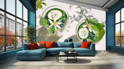 Refreshing summer drink - cucumber infused water with ice, sage, cucumber and lemon blossom on the table in the garden. Fresh healthy cold detox beverage. Fitness drink. Wall mural