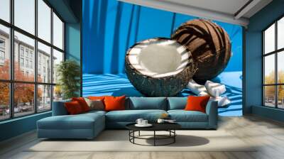 Ripe coconut on blue background with coconut tropical palm leaf shadow. Healthy stile life, food and summer holiday concept. Space for text. Wall mural