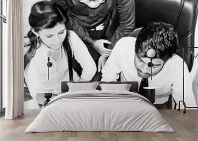 Team of two young men and one indian woman in the office Wall mural