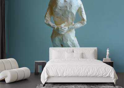 Back pain, the man is bent over and holding his hands behind his back, figure made of crumpled paper on blue background, unusual creative illustration Wall mural