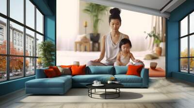 young mother with cute female children meditating and doing yoga exercise at home in the living room on the comfortable sunny day. Wall mural