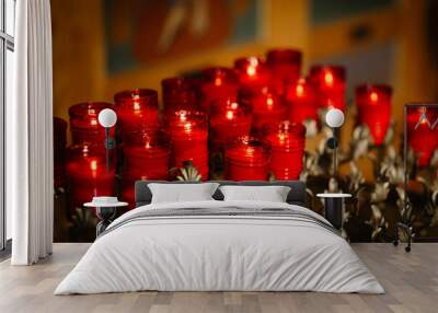 About twenty glowing red prayer candles in gold candle holders Wall mural