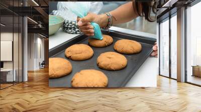 Girl decorating freshly baked cookies with a piping bag. Wall mural