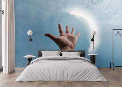 hand up in the air playing with the sunlight, blue background Wall mural