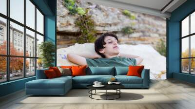 Handsome boy lying with eyes closed on the rock, vacation concept Wall mural