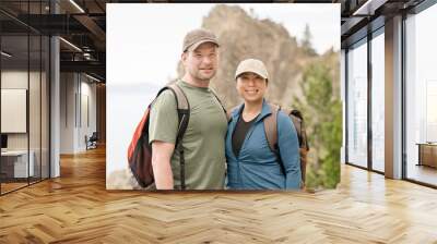 Hiker Couple smiling at the camera with mountain behind them Wall mural