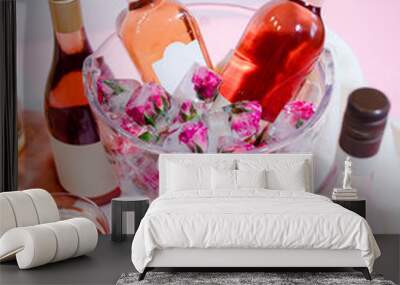 Mini roses frozen into ice cubes in wine bucket with bottles of Wall mural