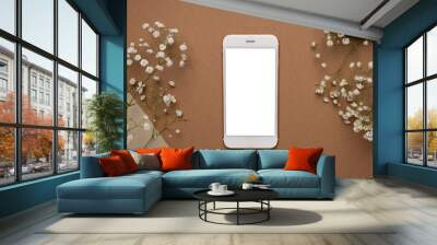 Mobile phone with white screen and dry flower branch and stone on a light brown background. Trend, minimal concept with copyspace Wall mural