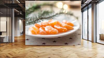 Plate with slices of tangerine on the table in daylight with lights ga Wall mural