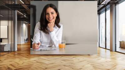 Portrait of young business woman smilling and writting Wall mural