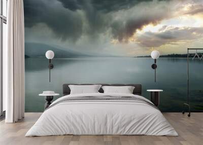 stormy landscape on mountain lake with clouds breaking open by the sun Wall mural