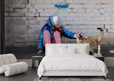 Teenage girl strokes cat the street. Concept of love for animals and environmental protection. Wall mural