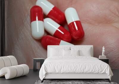 White and red capsules in macro view on hands Wall mural