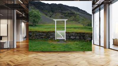 White wooden gate on a grassy hillside in Iceland Wall mural