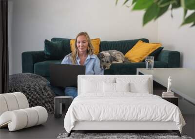 woman freelancer working on laptop with her dog at home Wall mural