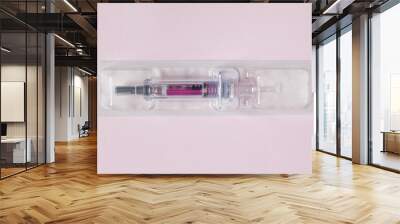 Individually sealed syringe pre-filled with a medical solution in a plastic blister on a textured pink paper background. Science health and medicine. Wall mural