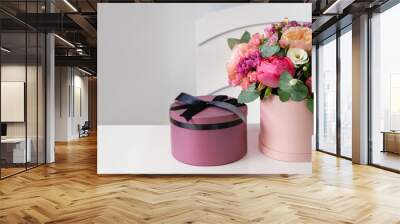 beautiful bouquet of flowers in round box and pink gift box on a white table Wall mural