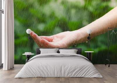 Close up of female hand in the rain with water drops on green blurred background. Wall mural