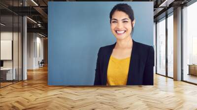 Confidence is the key to success. Studio portrait of an attractive young businesswoman standing against a blue background. Wall mural