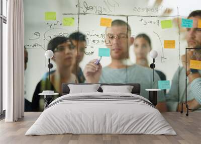 Group of creative business people brainstorm ideas on a glass board. Colleagues training, teamwork in a workshop or seminar for learning innovative startup company strategy in a meeting together Wall mural