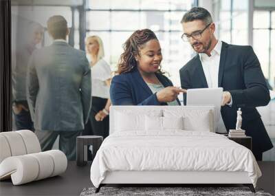 He trusts her business instincts. Shot of two coworkers talking together over a digital tablet in an office. Wall mural