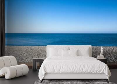 Seascape with pebble stone beach and sea defence wall on a beautiful day in Llandudno Wales UK Wall mural