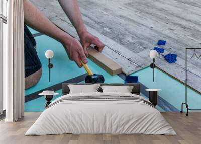 Man laying laminate flooring using a set of tools. Wall mural