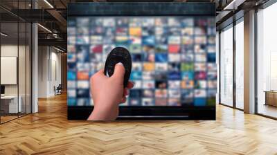 Multimedia streaming concept. Hand holding remote control. TV screen with lot of pictures. Wall mural