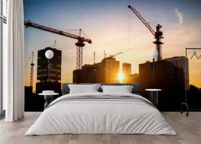 New construction site with crane and mechanical equipments on sunset background. Construction site crane. Silhouette building site. Wall mural