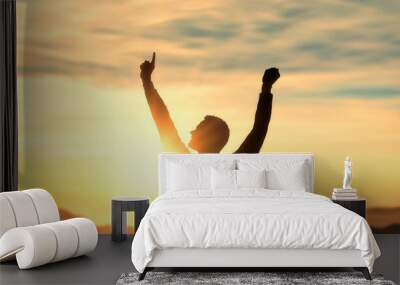 Success, achieving goals in business and life, feeling of triumph. , symbol of achievement. silhouette of man on top of mountain with his arms raised in triumph at sunset, joy and satisfaction Wall mural