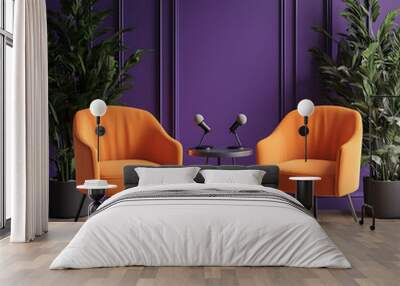 Two orange armchairs face each other across a small table with two microphones. Purple walls and potted plants are in the background. Wall mural