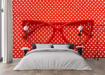 Pair of red cat eye shape women's glasses on a red polka dot background. Eye health concept. Wall mural